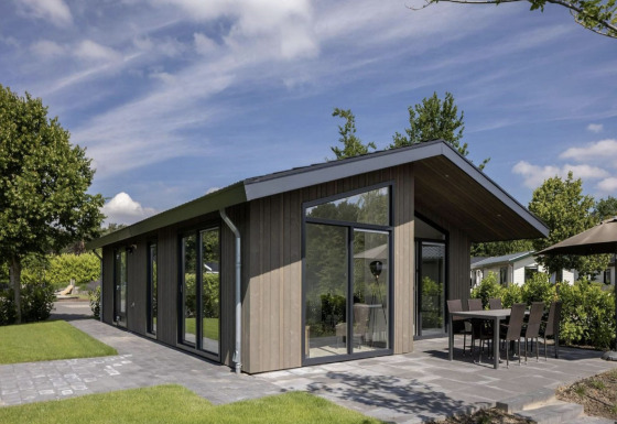 Chalet moderno con ampie vetrate all’Holiday Park Molenvelden 7, circondato da giardini e patio esterno.