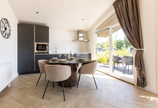 Helles, modernes Chalet-Küchen- und Essbereich im Holiday Park «Molenvelden 7» in den Niederlanden mit Terrassenzugang.