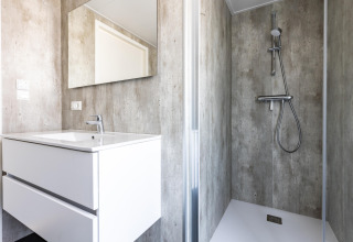 Baño moderno en el chalet Holiday Park «Molenvelden 7» en los Países Bajos con lavabo, espejo y ducha.