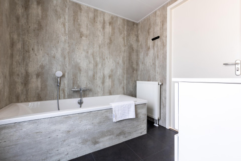 Modernes Badezimmer im Holiday Park «Molenvelden 7» mit Badewanne, Heizung und neutralen Farben, Niederlande.