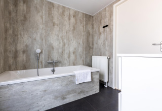 Modernes Badezimmer im Holiday Park «Molenvelden 7» mit Badewanne, Heizung und neutralen Farben, Niederlande.