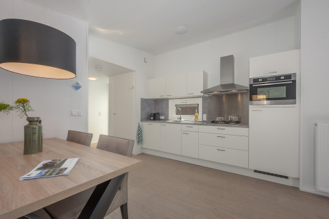 Cocina moderna y comedor en la cabaña Forest Park 't Wolfsven 9 en Países Bajos, con muebles elegantes y luz suave.