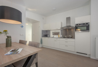 Cocina moderna y comedor en la cabaña Forest Park 't Wolfsven 9 en Países Bajos, con muebles elegantes y luz suave.