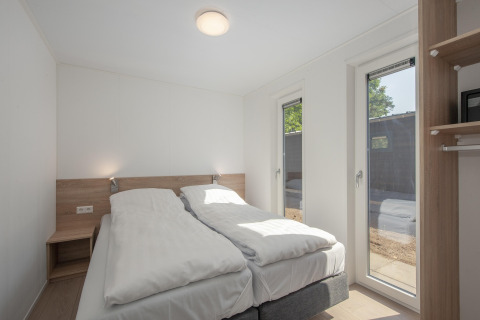 Dormitorio luminoso y moderno en Forest Park 't Wolfsven 9, Países Bajos, con dos camas y grandes ventanas.