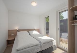 Bright, modern bedroom at Forest Park 't Wolfsven 9 in the Netherlands, featuring twin beds and tall windows.