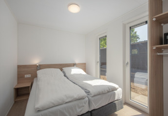 Dormitorio luminoso y moderno en Forest Park 't Wolfsven 9, Países Bajos, con dos camas y grandes ventanas.