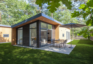 Moderne træhytte i skovmiljø i Forest Park 't Wolfsven 9, Holland, med terrasse og havemøbler.
