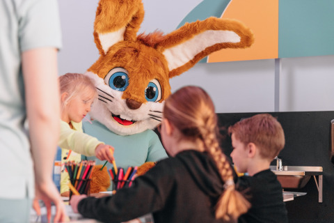 Kinder basteln am Tisch mit einem großen Kaninchenkostüm im Forest Park 't Wolfsven 9 in den Niederlanden.