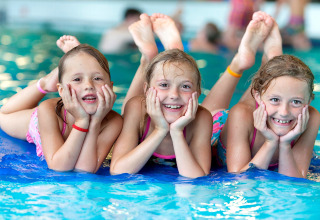 Tre bambini felici giocano in piscina durante un soggiorno in una struttura glamping.