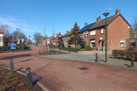 Día soleado en Forest Park 't Wolfsven 9 en los Países Bajos, con casas de ladrillo rojo en una calle tranquila.