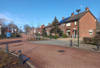Sonniger Tag im Forest Park 't Wolfsven 9 in den Niederlanden, mit roten Backsteinhäusern entlang der Straße.