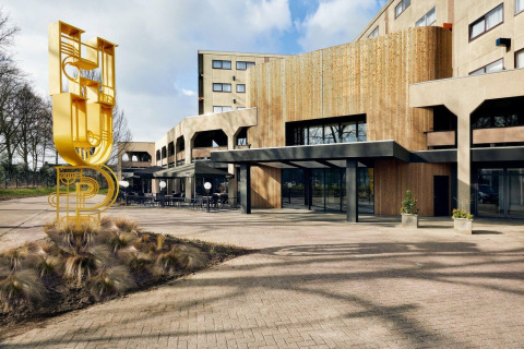 Ingresso di Forest Park «'t Wolfsven 9» in Olanda con facciata moderna in legno e scultura gialla HUB.