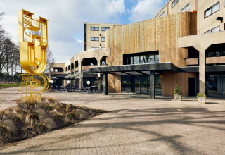 Eingang zum Forest Park «'t Wolfsven 9» in den Niederlanden mit moderner Architektur und gelber HUB-Skulptur.