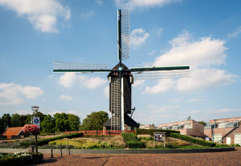 Traditionele Nederlandse windmolen bij Forest Park 't Wolfsven 9, omgeven door bloemen en blauwe lucht.