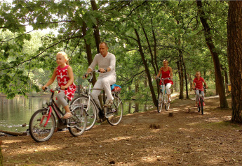 Famille faisant du vélo le long d’un lac dans une forêt, profitant d’un séjour en glamping.