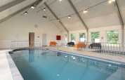 Piscina coperta in una sistemazione glamping luminosa con sedute moderne e ampie finestre.