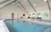 Indoor swimming pool at a bright glamping accommodation with modern seating and large windows.