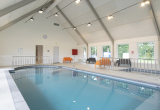 Piscina coperta in una sistemazione glamping luminosa con sedute moderne e ampie finestre.