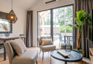 Soggiorno moderno in una tiny house con grandi finestre e vista sul bosco nei Paesi Bassi.