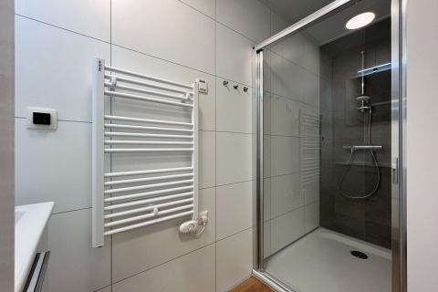 Bagno moderno con doccia, scaldasalviette e piastrelle chiare presso Forest Park ’t Wolfsven 20, Paesi Bassi.