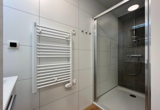 Baño moderno con ducha, radiador toallero y azulejos claros en Forest Park ’t Wolfsven 20, Países Bajos.