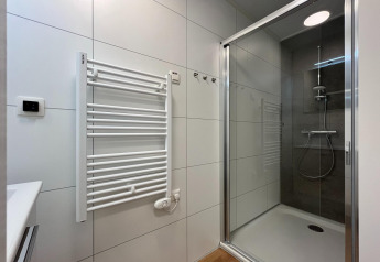 Modern bathroom with shower, towel radiator, and light tiles at Forest Park ’t Wolfsven 20, Netherlands.