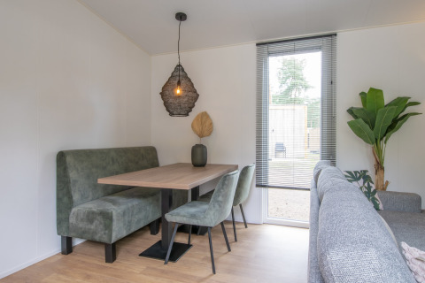 Zona de comedor en Forest Park 't Wolfsven 19 en Países Bajos con banca verde, mesa y planta decorativa.