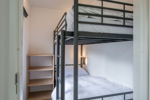 Small bedroom with bunk beds and shelving at Forest Park 't Wolfsven 20, Netherlands, viewed in daylight.