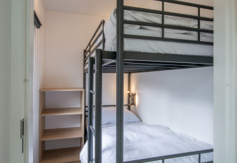Small bedroom with bunk beds and shelving at Forest Park 't Wolfsven 20, Netherlands, viewed in daylight.