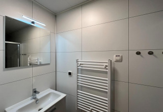 Baño moderno con espejo, lavabo, toallero calefaccionado y ganchos, Forest Park 't Wolfsven 20, Países Bajos.