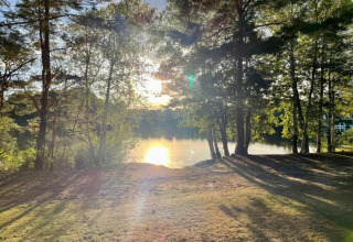 Atardecer sobre el lago en Forest Park 't Wolfsven 19, Países Bajos, rodeado de árboles y naturaleza.