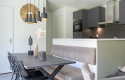 Comedor moderno y cocina con tonos grises, lámparas colgantes y decoración elegante, Forest Park 't Wolfsven 16.