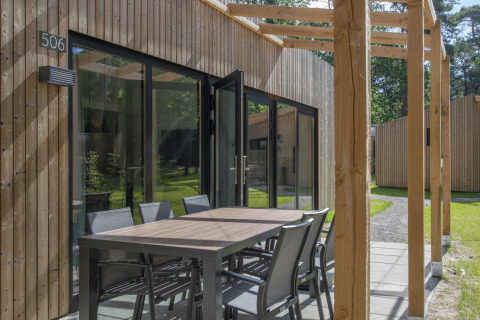 Zona de comedor exterior junto a una moderna cabaña de madera en Forest Park 't Wolfsven 16, Países Bajos.