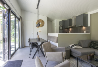 Moderne lodge med åbent køkken og stue ved Forest Park 't Wolfsven 16 i Holland med store vinduer.