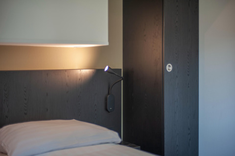 Interno camera moderna al Forest Park 't Wolfsven 16 con letto, lampada da lettura e pannelli in legno scuro.