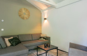 Salón moderno en chalet Forest Park 't Wolfsven 15, Países Bajos, con sofá gris y decoración de pared.