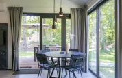 Comedor moderno con grandes ventanales y vista al bosque en Forest Park 't Wolfsven 15, Países Bajos.