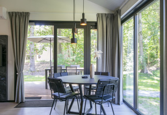 Comedor moderno con grandes ventanales y vista al bosque en Forest Park 't Wolfsven 15, Países Bajos.