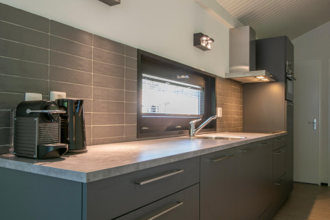 Cuisine moderne avec placards gris, fenêtre, cafetière et bouilloire à Forest Park 't Wolfsven 15 aux Pays-Bas.