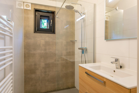 Bagno moderno con doccia a filo pavimento, piccola finestra e mobile in legno al Forest Park 't Wolfsven 15, Paesi Bassi.