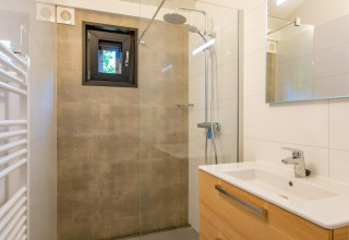 Salle de bain moderne avec douche à l’italienne, petite fenêtre et meuble en bois à Forest Park ’t Wolfsven 15, Pays-Bas.