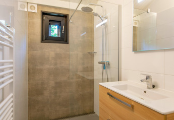 Baño moderno con ducha a ras de suelo, ventana pequeña y tocador de madera en Forest Park 't Wolfsven 15, Países Bajos.