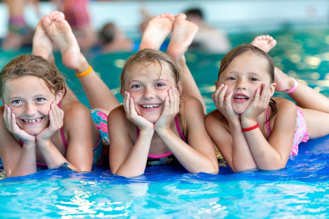 Tres niñas sonrientes junto a la piscina en Forest Park 't Wolfsven 15 en los Países Bajos, un día de verano.