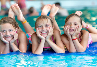 Trois filles souriantes allongées près de la piscine à Forest Park 't Wolfsven 15, aux Pays-Bas, un jour d'été.