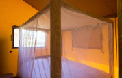 Innenansicht des Safari-Zeltes Forest Park 't Wolfsven 14 in den Niederlanden mit Bett und Moskitonetz.