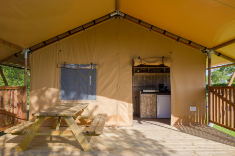 Veranda di tenda safari con tavolo in legno e angolo cottura al Forest Park 't Wolfsven 14 nei Paesi Bassi.