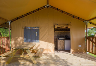 Veranda di tenda safari con tavolo in legno e angolo cottura al Forest Park 't Wolfsven 14 nei Paesi Bassi.