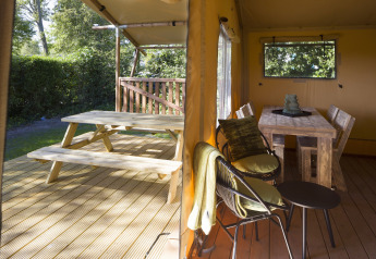 Vista de terraza de madera con mesa de picnic y área de comedor en el interior de una tienda safari.