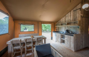 Intérieur d'une tente safari au Forest Park 't Wolfsven 13, Pays-Bas, avec meubles en bois et cuisine.