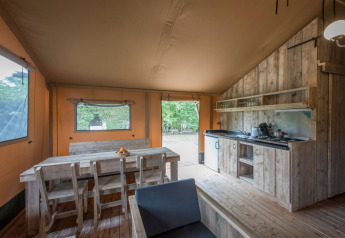 Intérieur d'une tente safari au Forest Park 't Wolfsven 13, Pays-Bas, avec meubles en bois et cuisine.